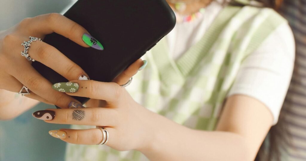 Two young women taking a selfie OF NAILS ART indoors with a smartphone. Casual and fun atmosphere.