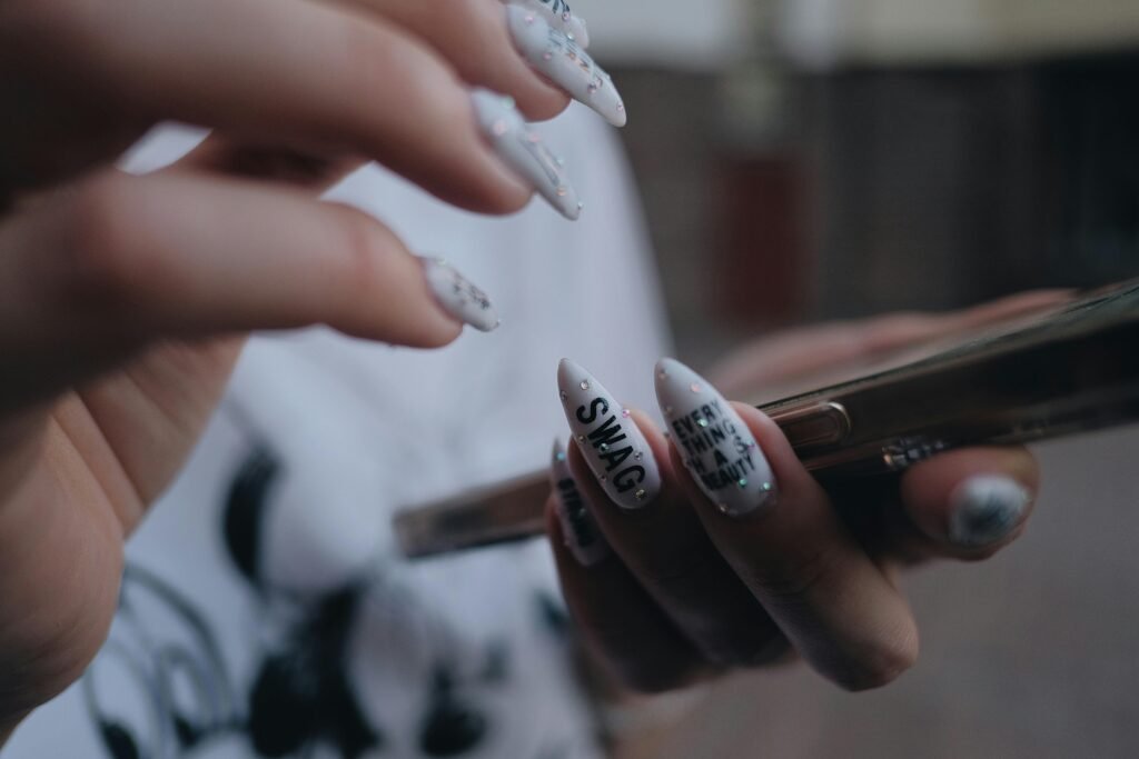 pexels-photo-8809259-8809259 Close-up image showcasing detailed nail art on hands holding a smartphone. Modern and trendy design.